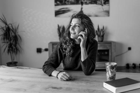 imagen en blanco y negro de una mujer sentada en una mesa hablando por teléfono